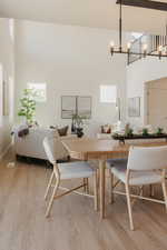 Dining area featuring a high ceiling, light wood finished floors, and suspended lighting