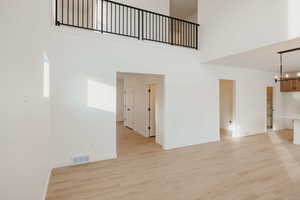 Unfurnished living room featuring light wood-style floors and suspended lighting