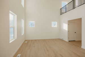 Unfurnished room featuring a high ceiling and light wood-style flooring