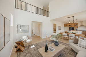 Living room with light wood-type flooring, recessed lighting, and a high ceiling