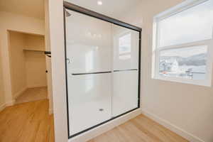 Bathroom with light wood-type flooring, a stall shower, and a spacious closet