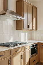 Kitchen with decorative backsplash, stainless steel appliances, and light wood finish cabinetry