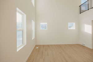 Spare room featuring a high ceiling and light wood-type flooring