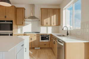 Two tone kitchen featuring stainless steel appliances, light stone counters, light wood finished floors, tasteful backsplash, and two tone cabinetry