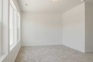 Spare room with light carpet and baseboards
