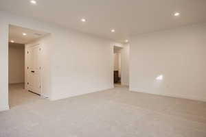 Empty room with light carpet and recessed lighting