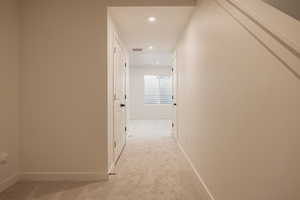 Corridor with light carpet and recessed lighting
