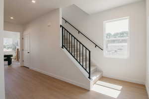 Staircase with wood finished floors, plenty of natural light, and recessed lighting