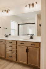 Bathroom featuring double vanity, light wood-type flooring, a shower stall, and recessed lighting