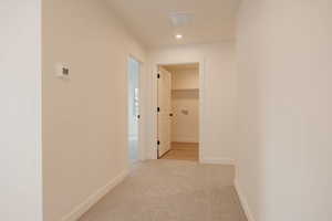 Hallway with light colored carpet and recessed lighting