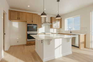 Kitchen with stainless steel appliances, light wood-style flooring, tasteful backsplash, hanging light fixtures, and a kitchen island