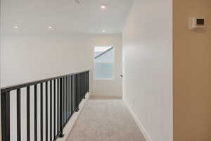 Hall with light colored carpet and recessed lighting
