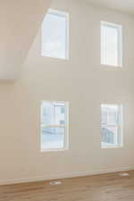 Spare room featuring a high ceiling and light wood-type flooring