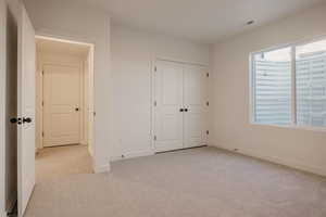 Unfurnished bedroom with light colored carpet and a closet