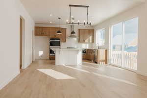 Kitchen with light countertops, stainless steel appliances, a breakfast bar, light wood-style floors, and a kitchen island