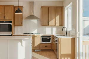 Kitchen featuring decorative backsplash, light stone counters, stainless steel appliances, and hanging light fixtures