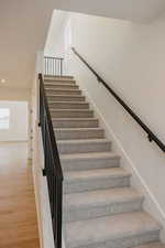 Stairs with wood finished floors and recessed lighting