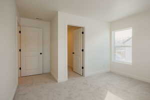 Unfurnished bedroom with light colored carpet and baseboards