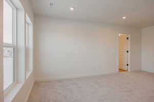 Empty room with light colored carpet, recessed lighting, and plenty of natural light