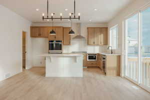 Kitchen with tasteful backsplash, stainless steel appliances, a breakfast bar area, pendant lighting, and light wood-style flooring
