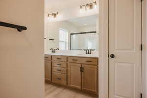Full bath featuring double vanity, light wood-type flooring, a shower stall, and a closet