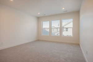 Empty room with light carpet and recessed lighting
