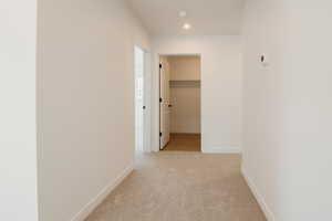 Hallway with light carpet and recessed lighting