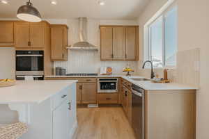 Two tone kitchen with stainless steel appliances, light wood finished floors, light stone countertops, two tone cabinets, and a breakfast bar area