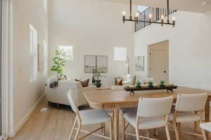 Dining room featuring light wood finished floors, a high ceiling, and suspended lighting