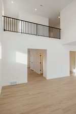 Spare room featuring a high ceiling, light wood-type flooring, and recessed lighting