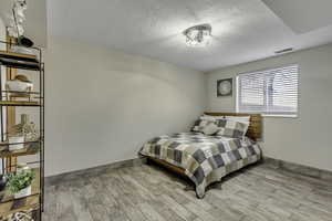 Bedroom with wood finished floors, a textured ceiling and new lighting