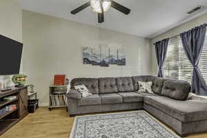 Living area with light wood finished floors and ceiling fan