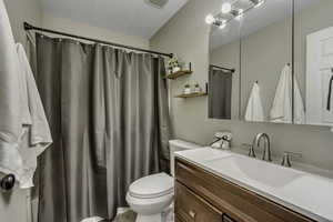 Full bath with vanity, a shower with curtain, and a textured ceiling