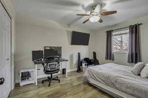 Bedroom with light wood-style flooring, a ceiling fan, an office area, a closet, and a textured ceiling
