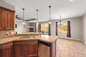 Kitchen with dishwasher, stone tile floors, a peninsula, a chandelier, and light stone countertops