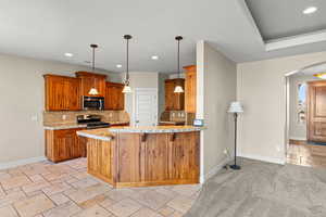 Kitchen with stone tile floors, arched walkways, wood finish cabinets, hanging light fixtures, and light stone counters