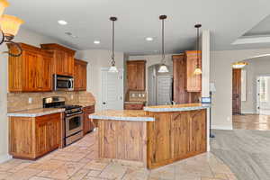 Kitchen with arched walkways, stainless steel appliances, pendant lighting, wood finish cabinets, and tasteful backsplash