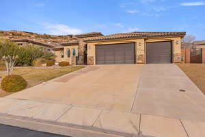Mediterranean / spanish home with a gate, stucco siding, stone siding, and an attached garage