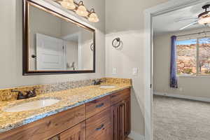 Full bathroom with double vanity, light carpet, and a ceiling fan