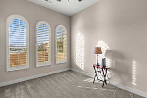 Carpeted empty room featuring baseboards and ceiling fan