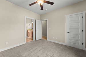 Unfurnished bedroom featuring light colored carpet, ceiling fan, and ensuite bath