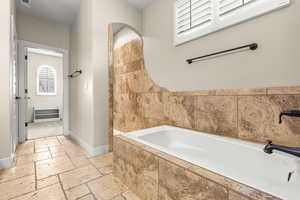 Bathroom with stone tile flooring and a bath