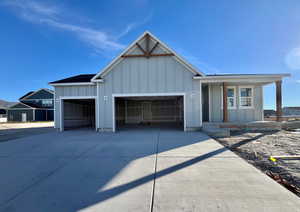 View of front of house featuring board and batten siding, covered porch, driveway, and an attached garage