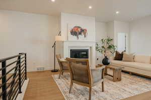 Living room with recessed lighting, light wood finished floors, and a glass covered fireplace