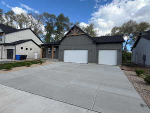 View of front of home with an attached garage, board and batten siding, concrete driveway, and covered porch
