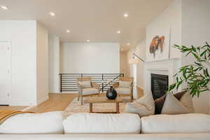Living area with light wood-type flooring, recessed lighting, and a glass covered fireplace