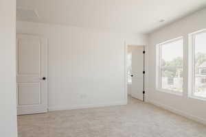Empty room with light colored carpet and baseboards