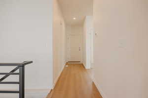 Corridor with light wood-style floors, recessed lighting, and an upstairs landing