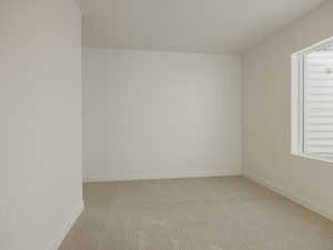Unfurnished room featuring light carpet and baseboards
