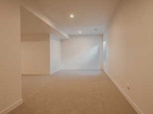 Empty room with light carpet and recessed lighting